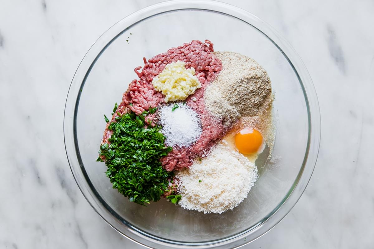ground sausage, ground beef, egg, bread crumbs, parmesan cheese, parsley, salt and garlic in a glass bowl