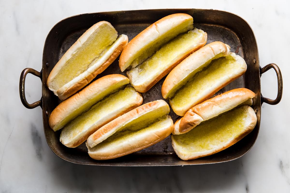 toasted hoagie rolls in a baking dish with butter