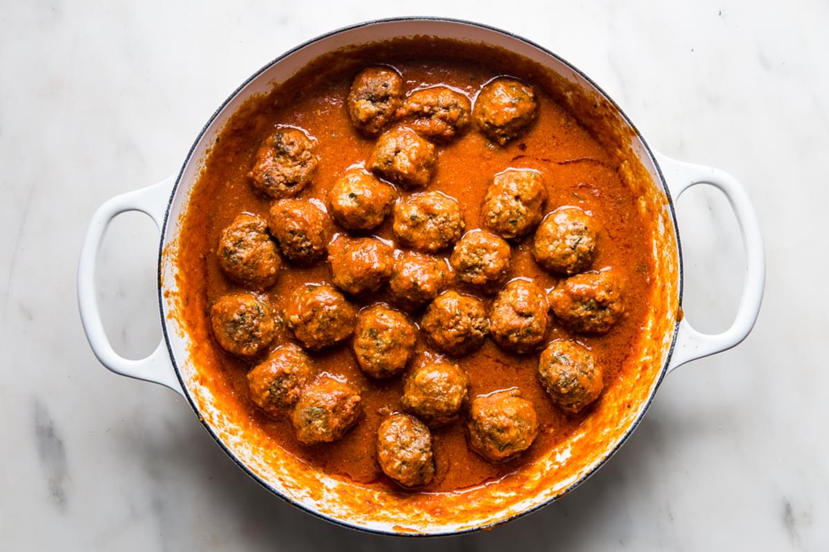 cooked Italian meatballs simmered in a braiser with marinara sauce