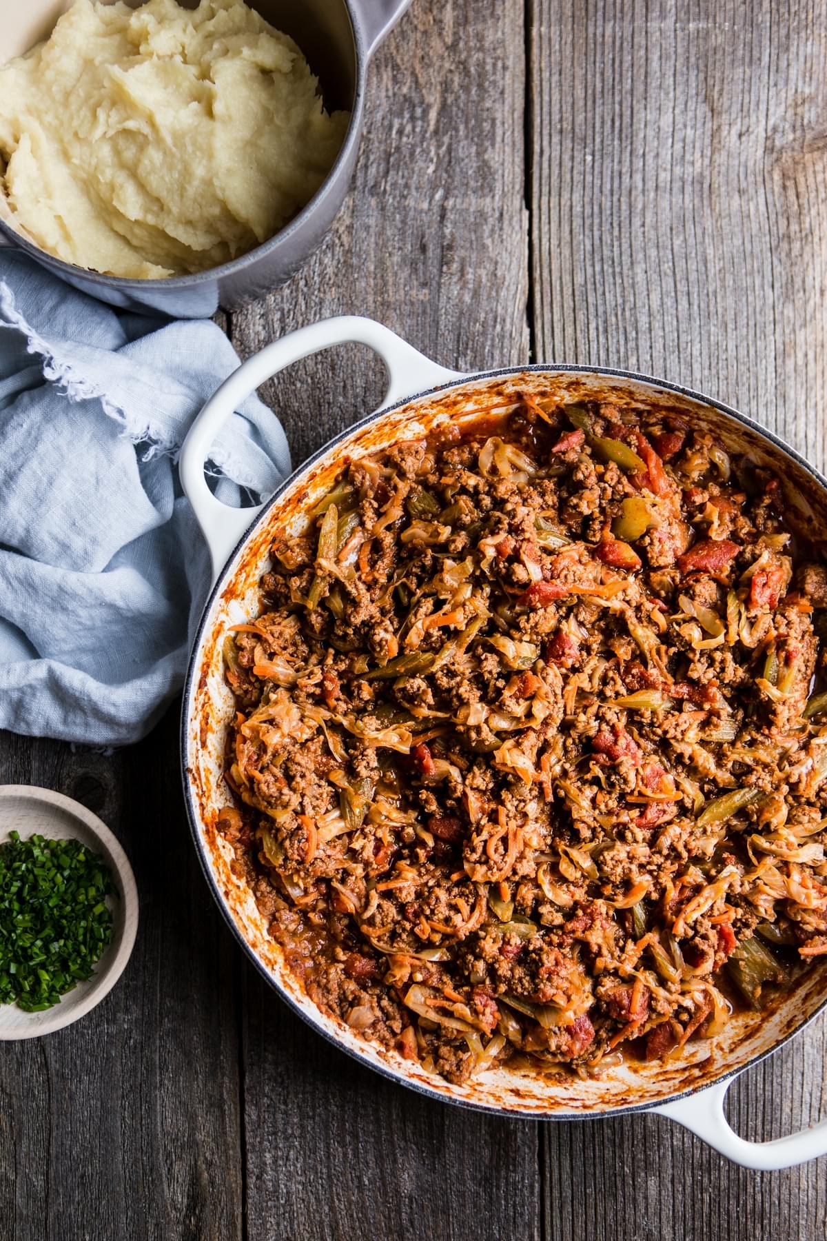 ground beef, vegetables and tomatoes cooked down in a pan for shepherd's pie