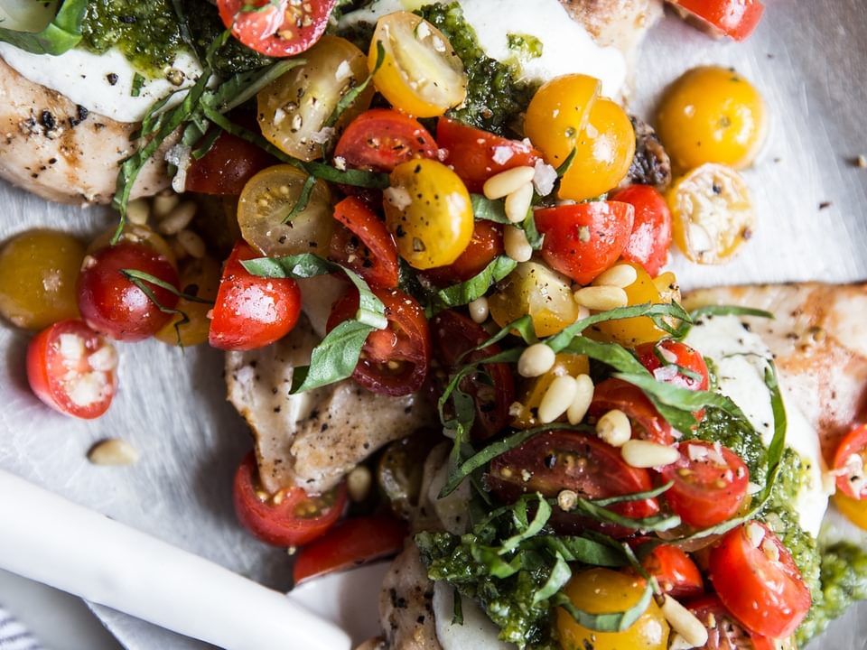 Pesto chicken bruschetta with cherry tomatoes, basil and pine nuts on a plate