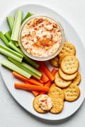 homemade pimento cheese in a bowl on a serving platter with celery, carrots and ritz crackers