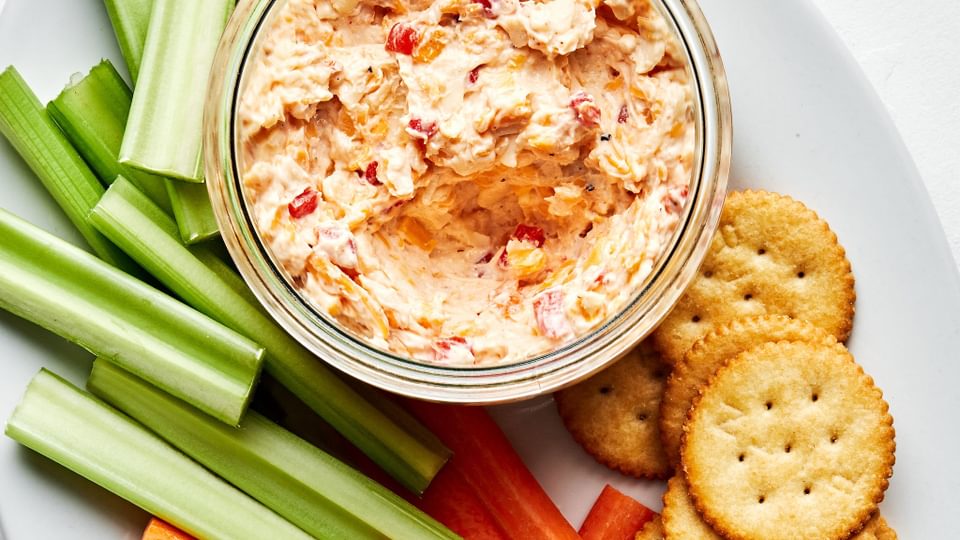 homemade pimento cheese in a bowl on a serving platter with celery, carrots and ritz crackers