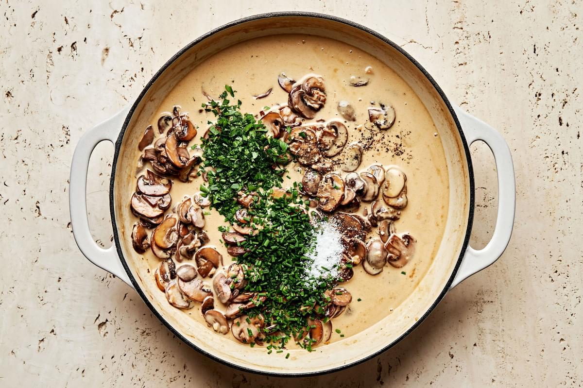 pasta, chives, parsley, salt and pepper being added to a pot with homemade mushroom sauce