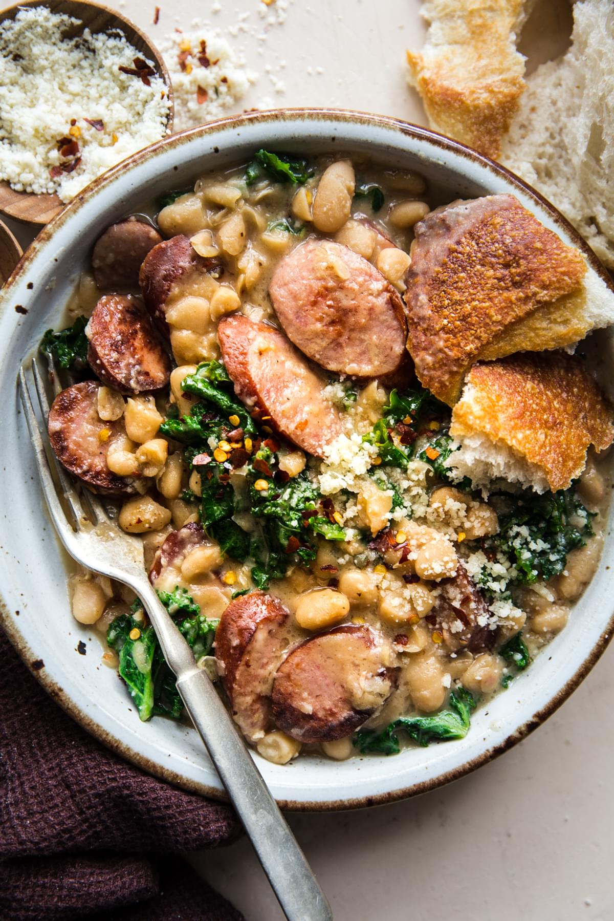 white bean and sausage skillet dinner with kale in a bowl served with crusty bread