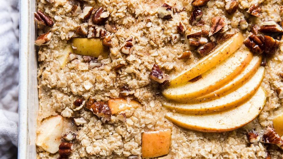 Baked Oatmeal with Apples in a baking dish with pecans and maple syrup