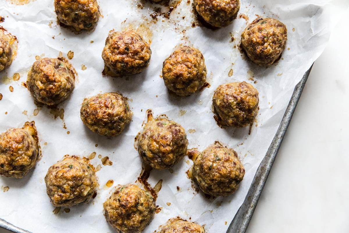 Baked Meatballs on a baking sheet made with ground pork, eggs, ginger, garlic breadcrumbs, green onions, and salt