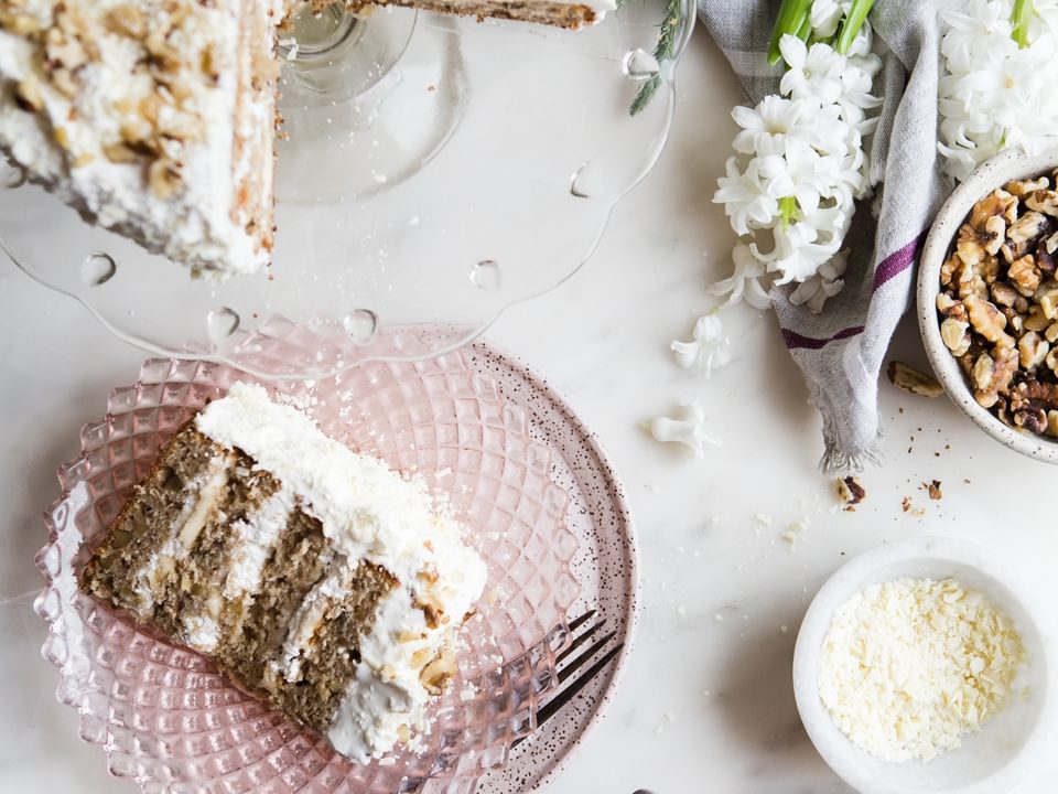 banana walnut cake on a cake stand with two slices on plates