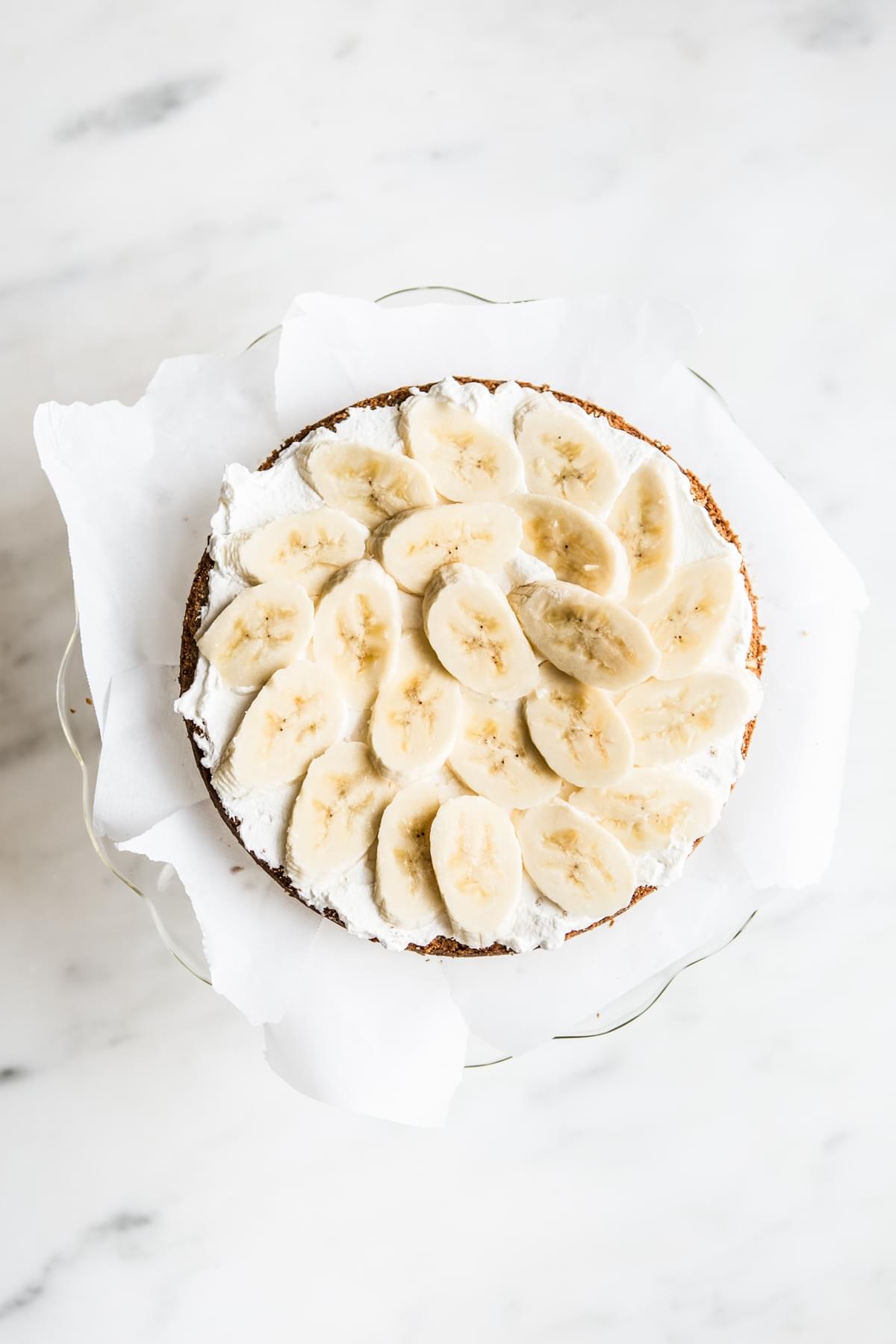 whipped frosting cream and banana slices on top of a layer of banana cake