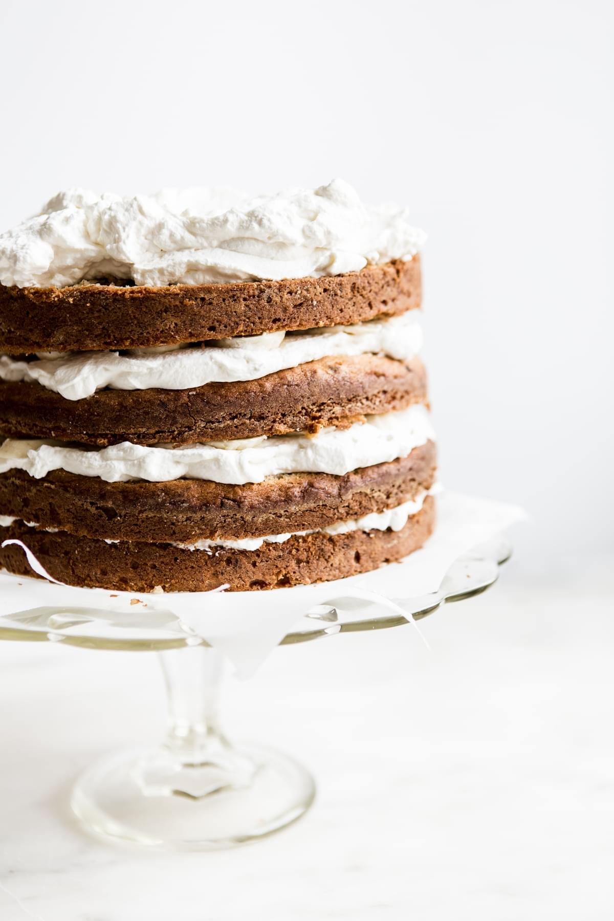 a 4 layer banana cake with whipped cream frosting on a cake stand