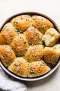 Butter And Herb dinner Rolls in a pan with a linen