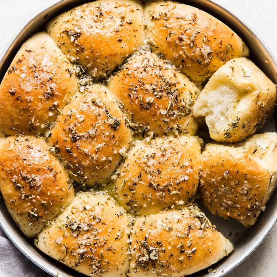 Butter And Herb dinner Rolls in a pan with a linen
