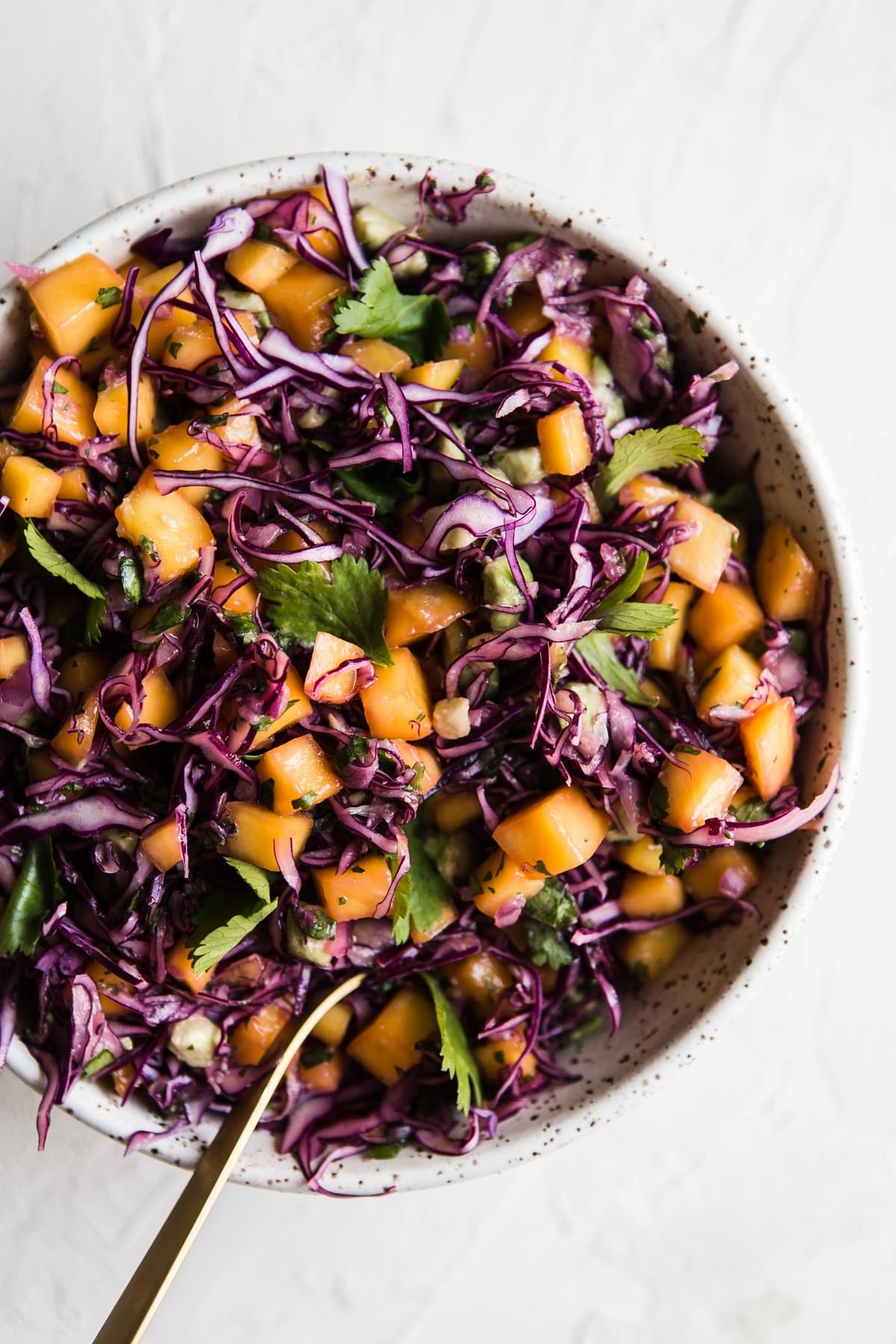 mango and red cabbage slaw in a bowl with cilantro