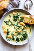 coconut curry lentil soup with kale and sweet potatoes in a bowl with a spoon