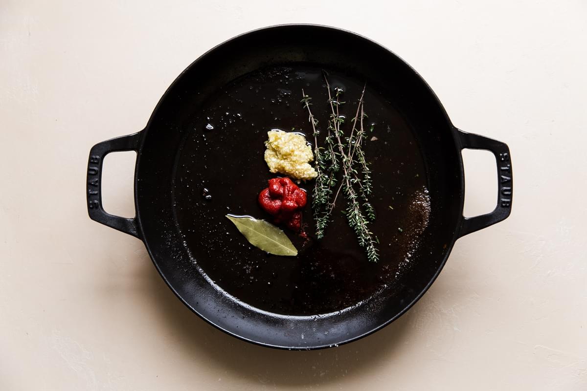 garlic, tomato paste, bay leaf and thyme in a braising dish