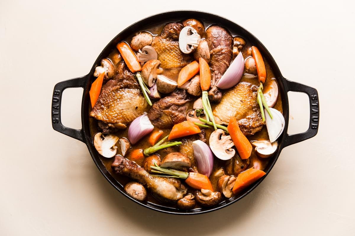 chicken coq au vin in a pot with carrots, shallots, mushrooms