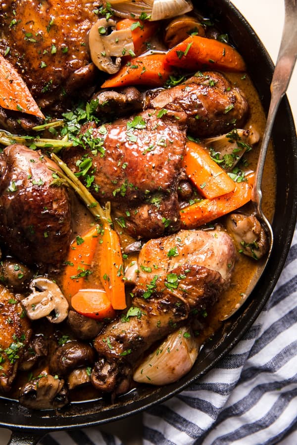 Coq Au Vin with carrots, mushrooms and chicken in a pot with a spoon