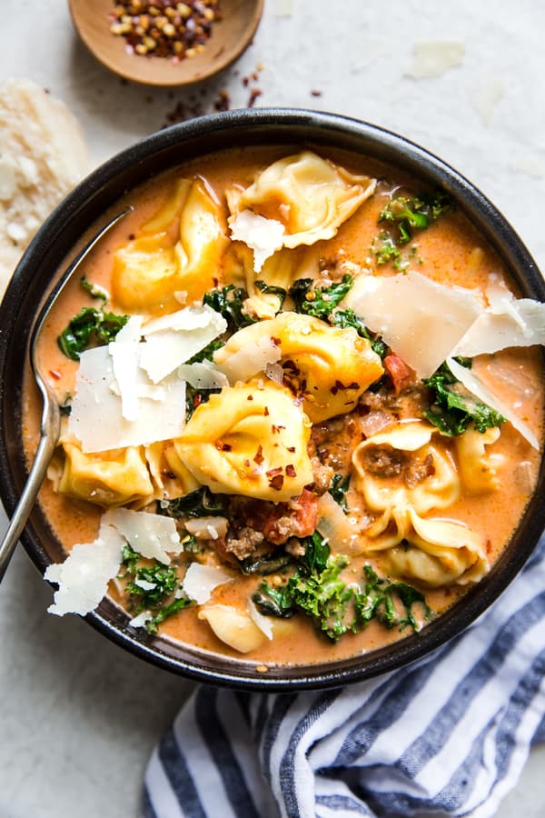 Tortellini soup with sausage and kale topped with fresh parmesan in a bowl