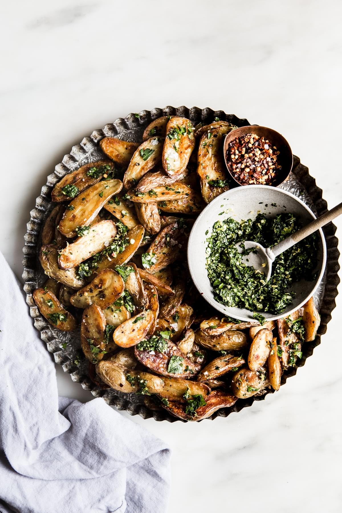 Crispy Roasted Potatoes With Gremolata on a platter with a bowl of gremolata