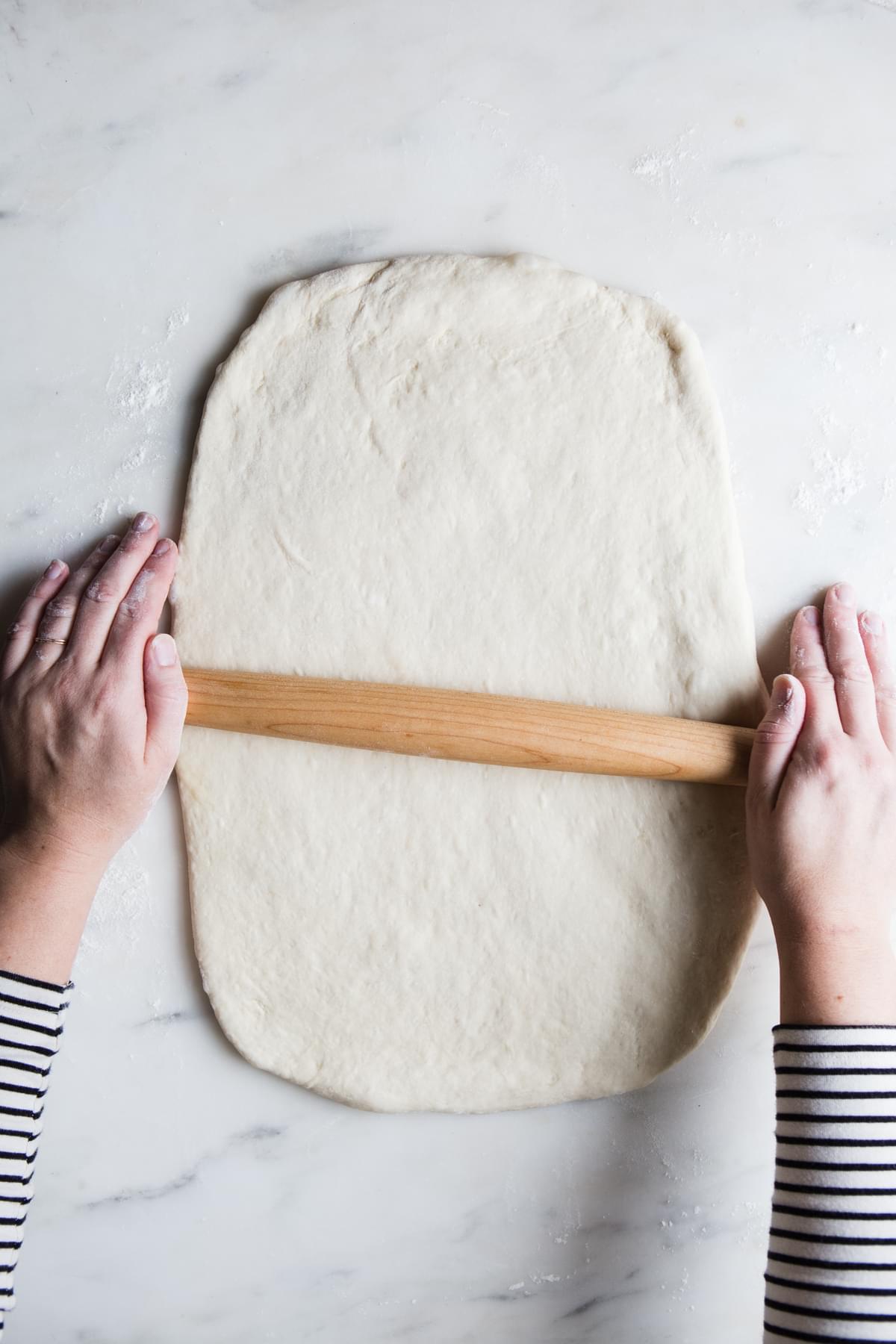 hands rolling out dough for dairy free cinnamon rolls