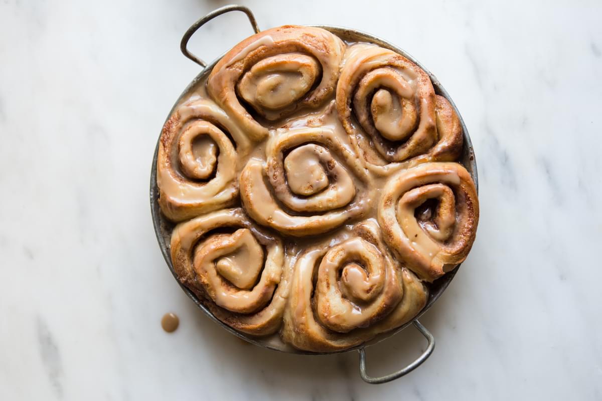 homemade Dairy free cinnamon rolls in a pan with maple frosting that's vegan