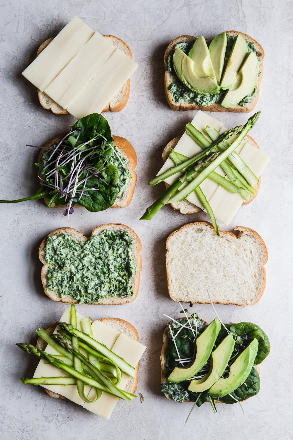 slices of bread with spinach, avocado, mozzarella cheese slices, green goddess spread and asparagus