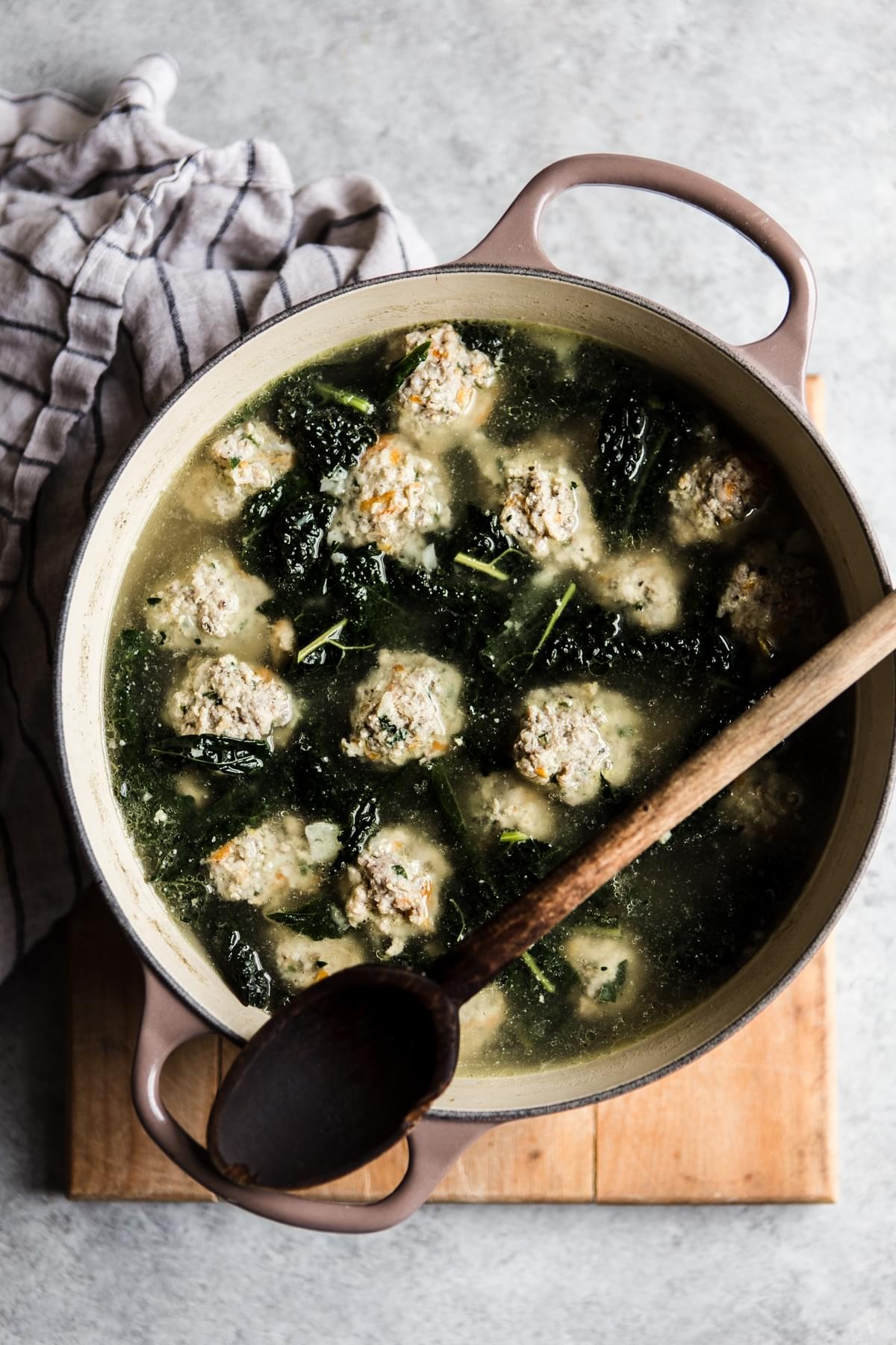 a large pot of Italian wedding soup that is made with chicken and pork meatballs and kale, whole30 and paleo with a spoon