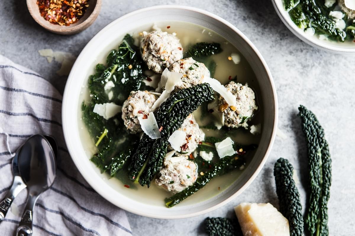 Healthy Italian Wedding Soup in a bowl with kale and pork and chicken meatballs, and chicken stock
