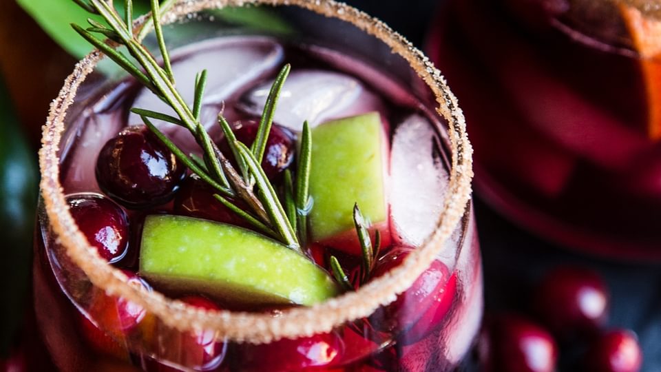 Red wine sangria with apples cranberries and oranges in a sugar rimmed glass