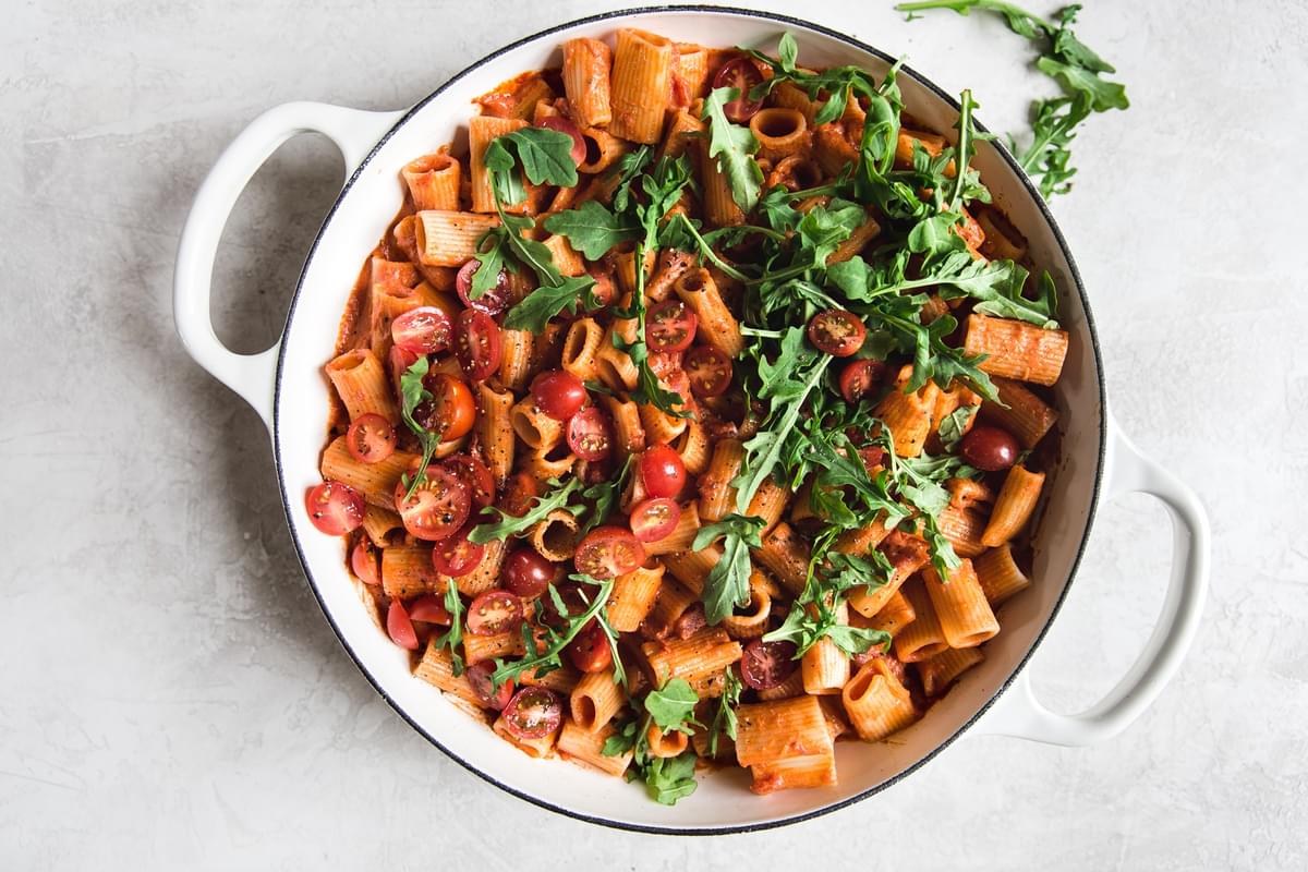 pasta with tomato cream sauce with cherry tomatoes and arugula in a pan