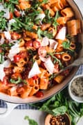 pasta with tomato cream sauce in a braiser with arugula and basil and parmesan