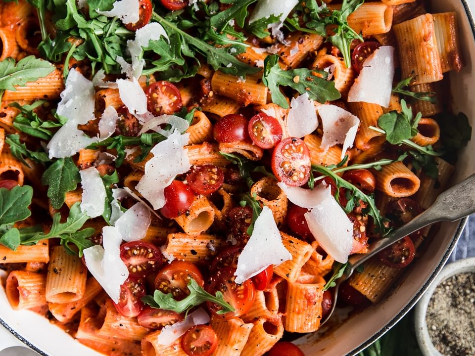 pasta dish with tomato cream sauce arugula and parmesan