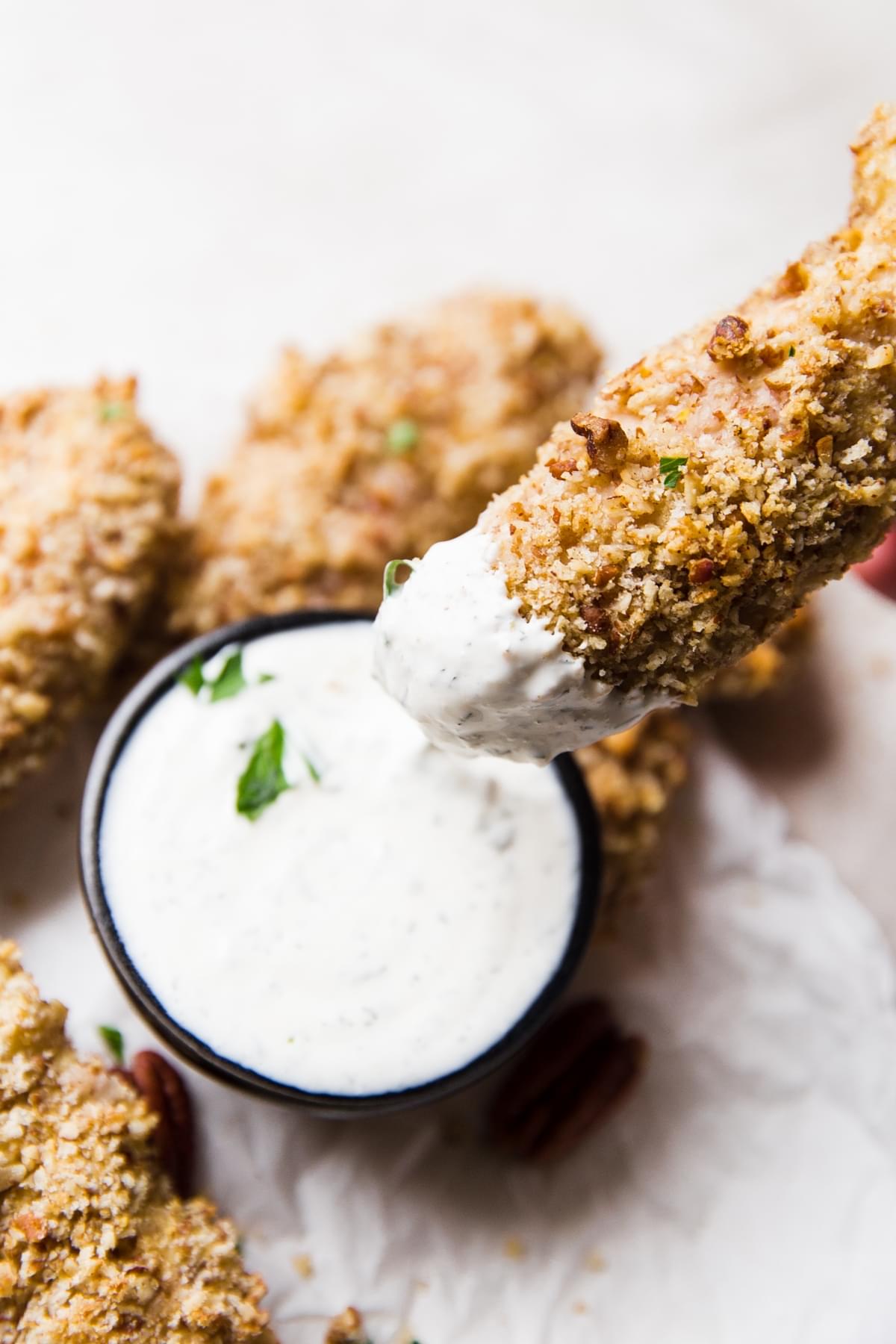 Chicken finger being dipped into ranch dressing