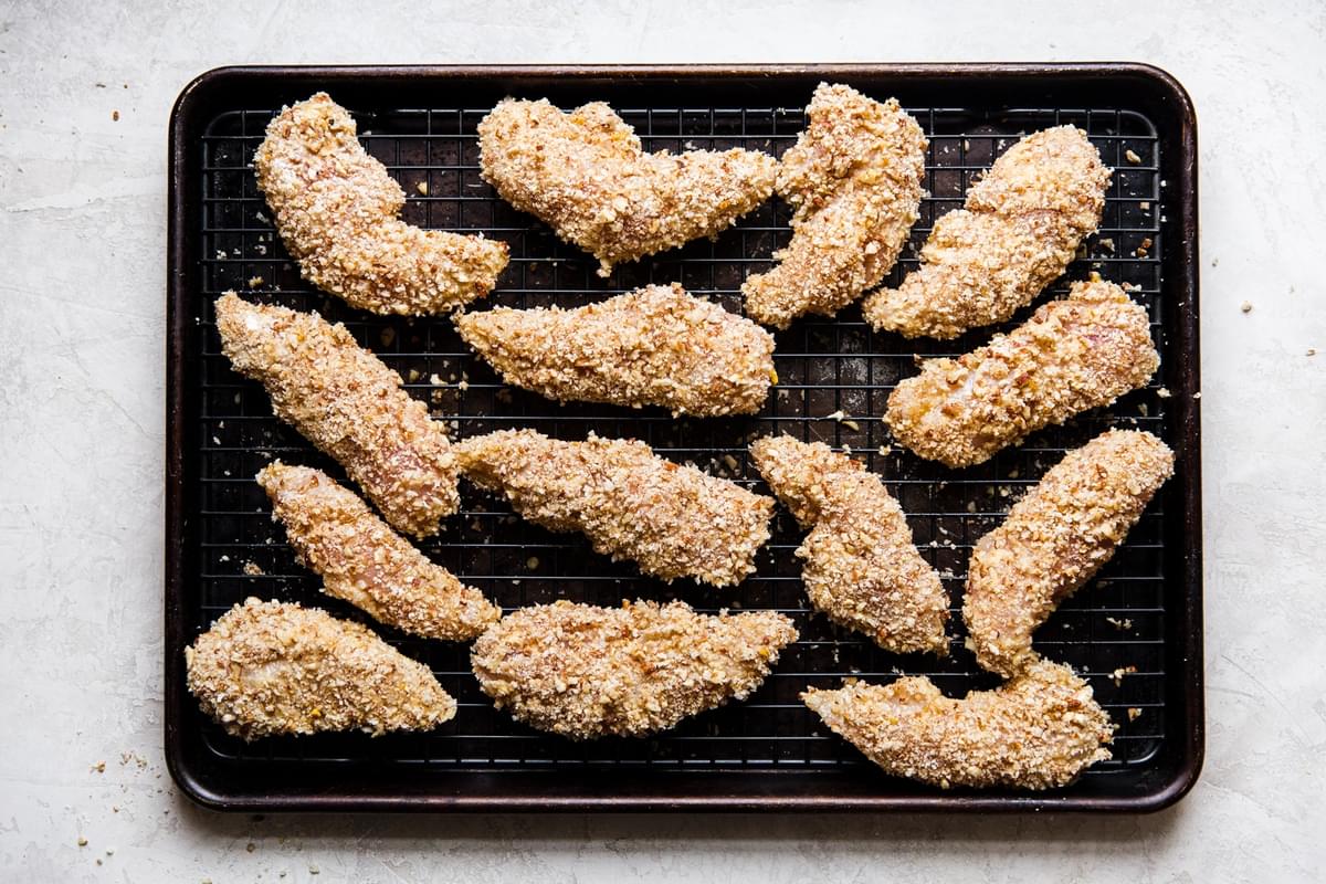 raw pecan crusted chicken strips on a baking sheet