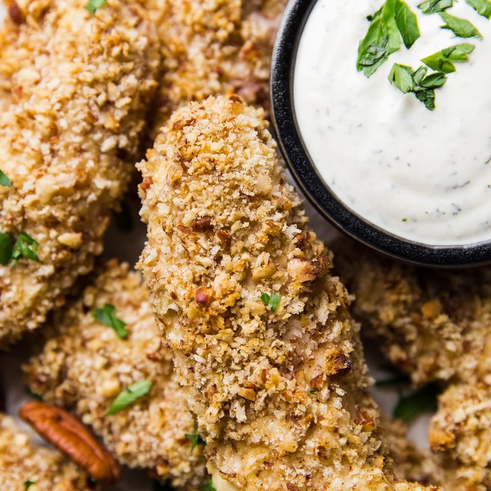 Pecan Crusted Chicken Tenders with buttermilk ranch in a small bowl