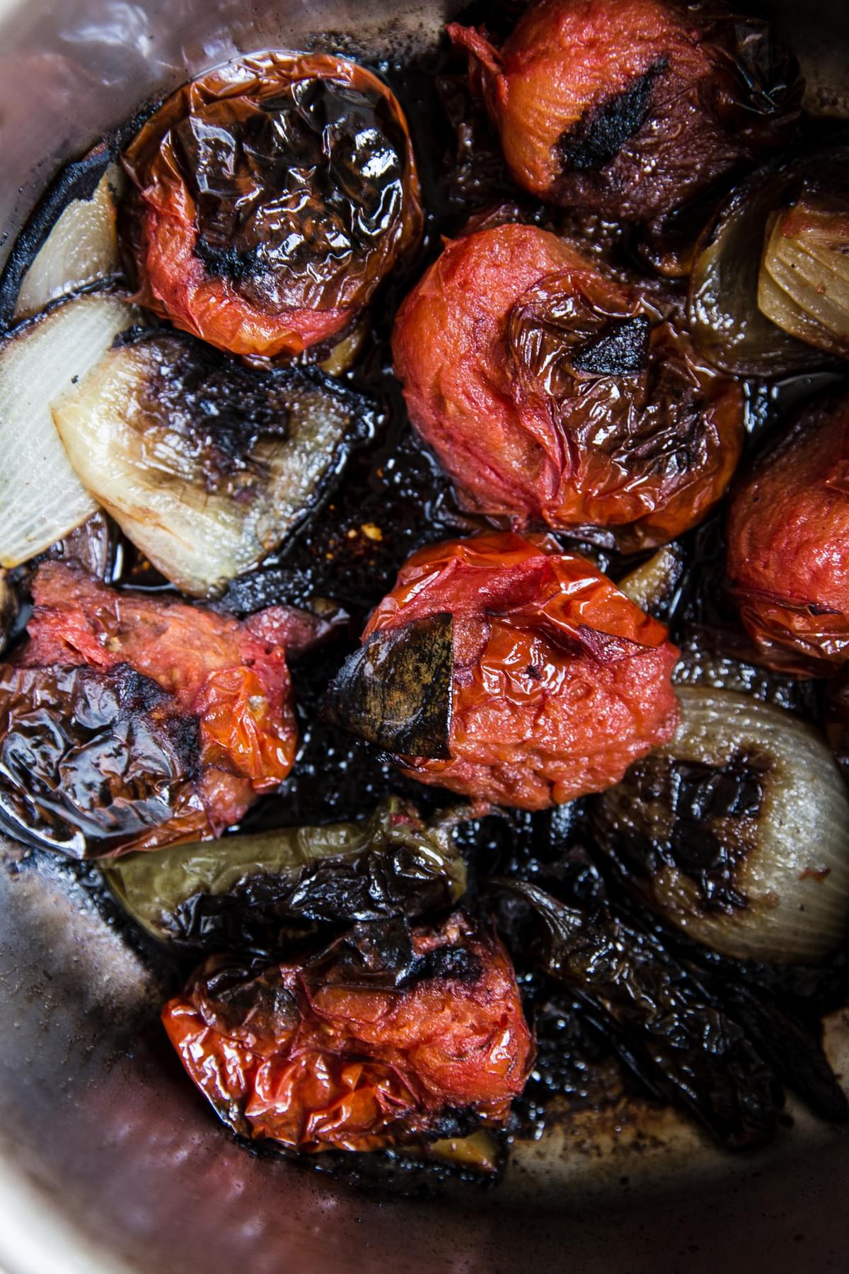 charred tomatoes and onions and jalapeños in a pan