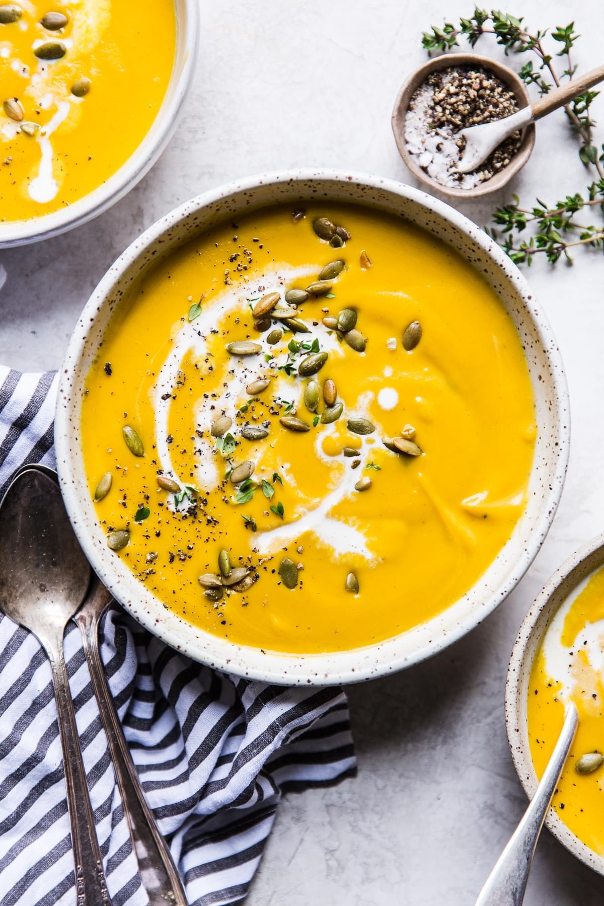 Roasted Butternut Squash Soup With Apples in 3 bowls with a striped linen and a spoon