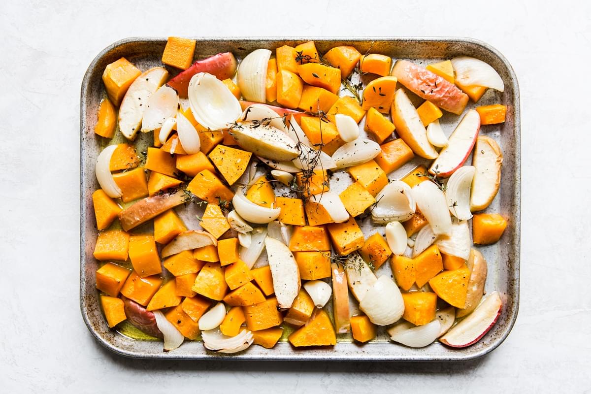 chopped up butternut squash, onions and apples on a baking sheet for Roasted Butternut Squash Soup With Apples