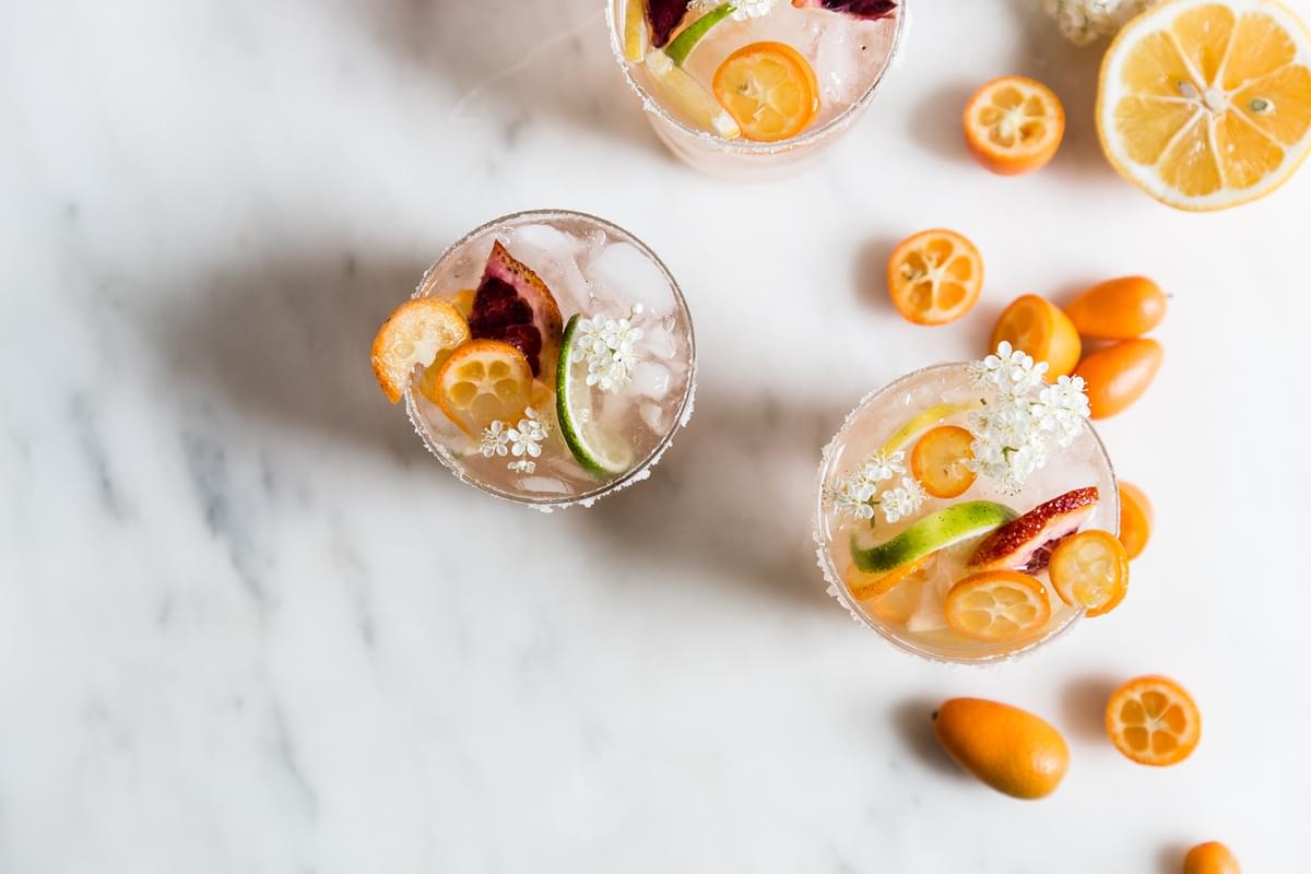 Rosé wine sangria in 3 cups with citrus fruit and flowers