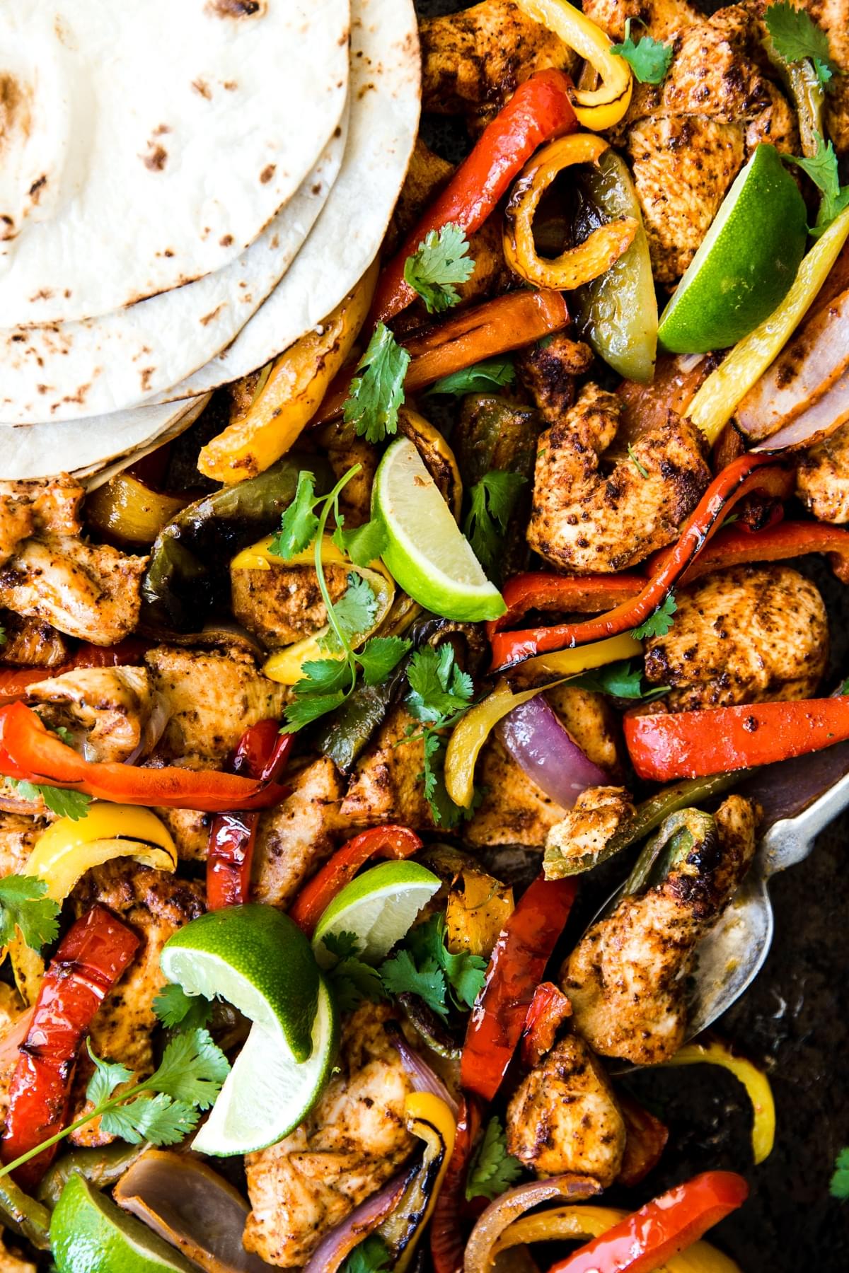 Chicken Fajitas on a sheet pan with onions, bell peppers, tortillas and a marinade.