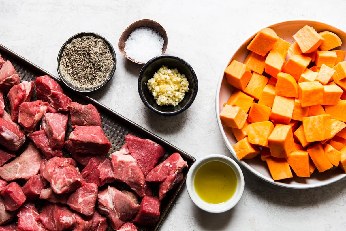 ingredients laid out for steak bites sweet potatoes, garlic, salt and pepper, olive oil and steak pieces.
