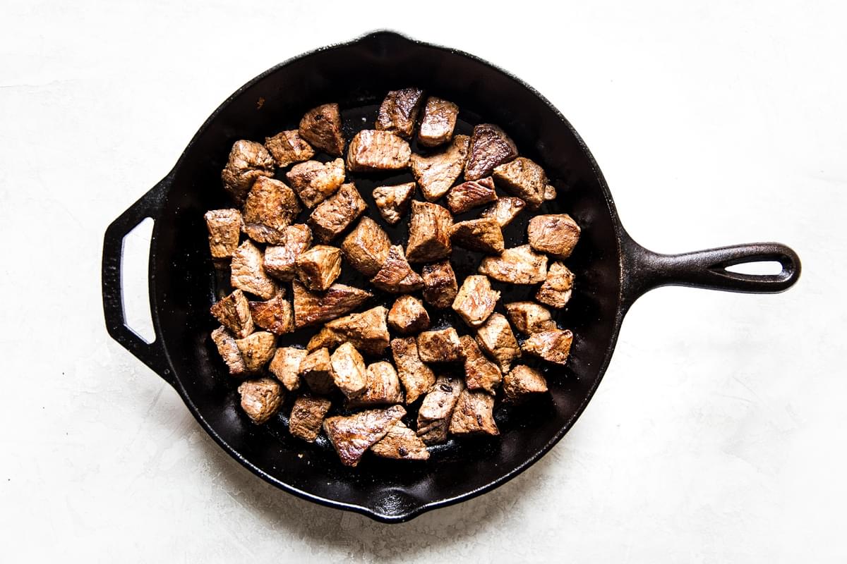 steak bites browned in a cast iron pan.