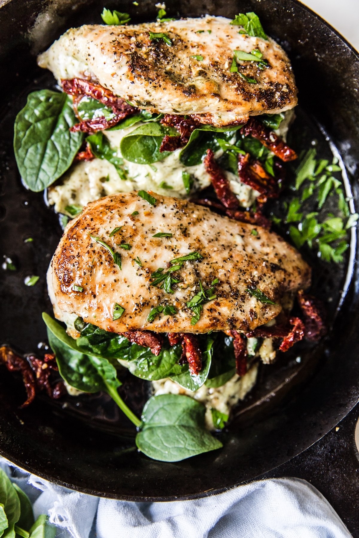 stuffed chicken breast with cream cheese pesto and sundries tomatoes in a cast iron skillet