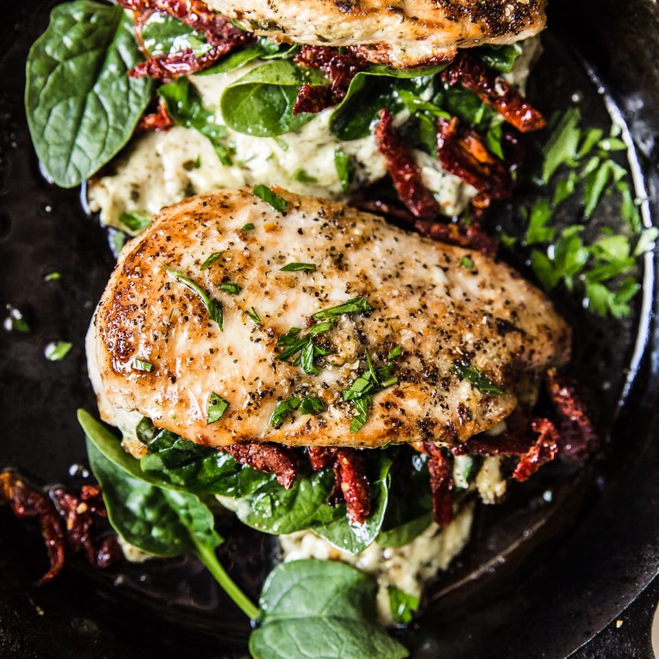 stuffed chicken breast with cream cheese pesto and sundries tomatoes in a cast iron skillet