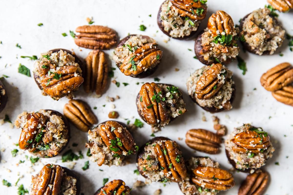 Goat Cheese And Pecan Stuffed Mushrooms spread out on a table with parsley.