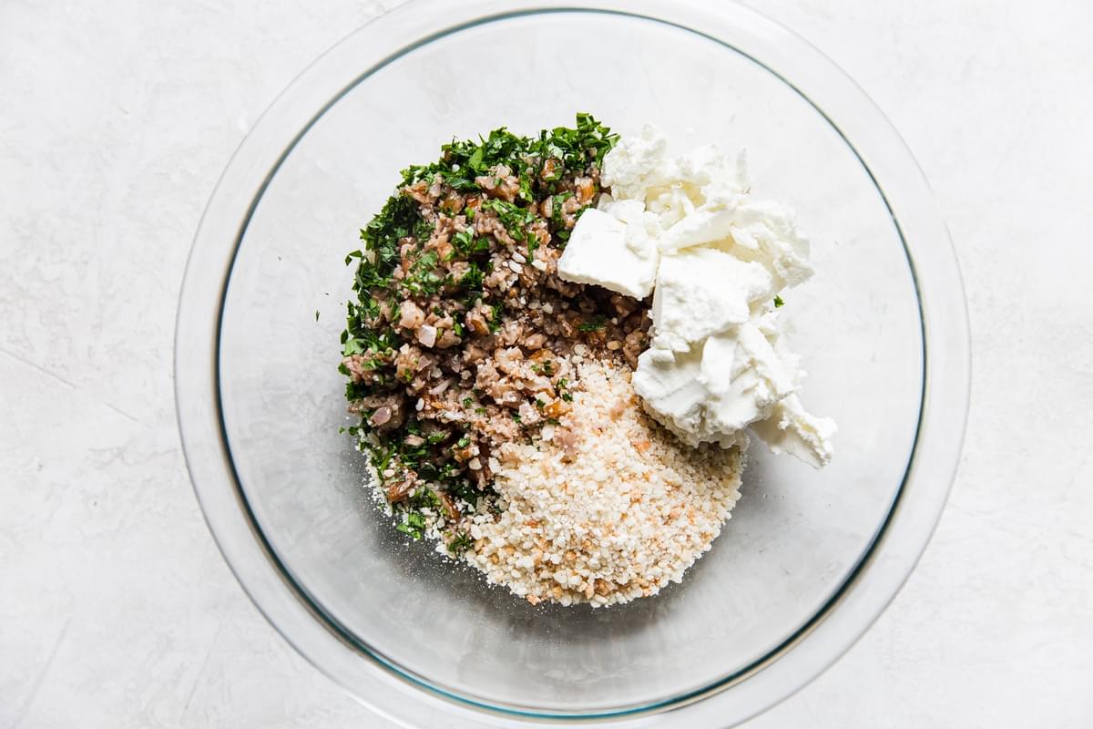 cooked mushroom caps with garlic and pecans in a bowl with goat cheese, bread crumbs and parsley