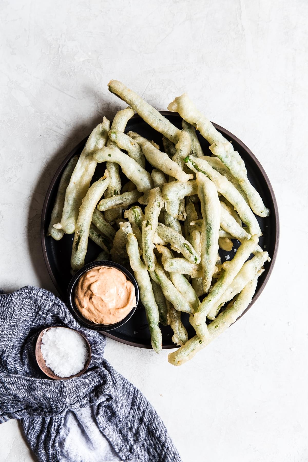 Tempura Green Beans With Curry Mayonnaise on a plate with salt and a linen