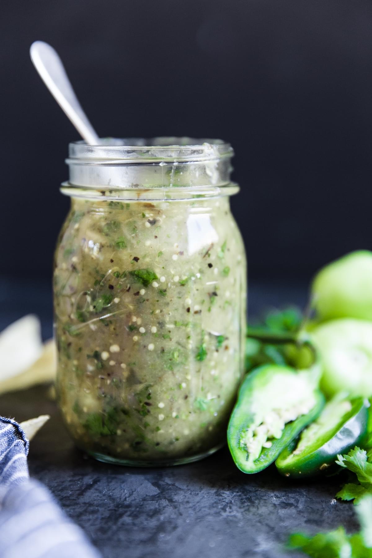 Green salsa in a jar with jalapeños