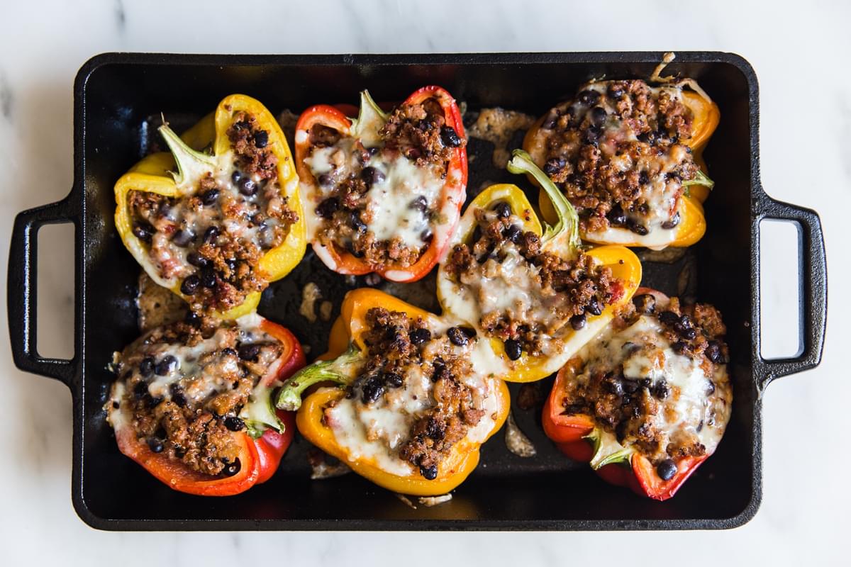 turkey and quinoa stuffed bell peppers in a baking dish topped with melted cheese
