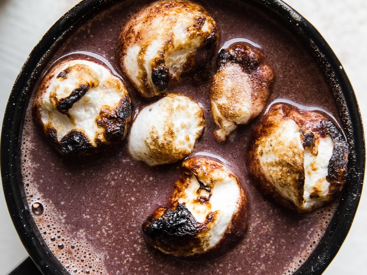 black mug of adult hot chocolate topped with toasted marshmallows